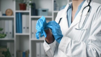 The doctor wears blue gloves before examining a patient. Stylish medical hands of a woman doctor. A medical employee puts gloves on his hands while in the reception office

