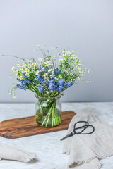 Blumenstrauss mit Muscari, Kamille und Ginster in Glasvase, Blumenvase Frühling