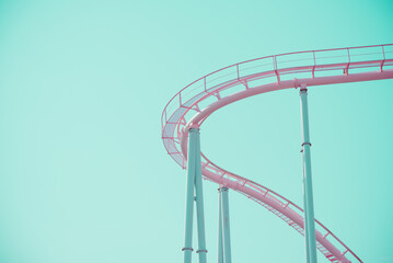 Pink pastel looping roller coaster on blue sky sunny day retro tone. Enjoy travel holiday concept.