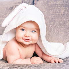 Smiling infant baby with towel after bathing. Care concept