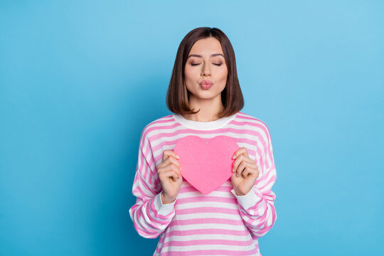 Photo of flirty brunette millennial lady hold heart blow kiss wear pink shirt isolated on blue color background