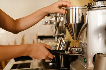 Young barista making coffee while working in cafe