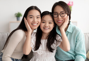 Portrait of cheerful multi generation Asian family posing and smiling at camera indoors
