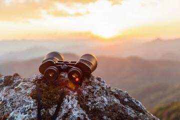 binoculars on top of rock mountain at sunset - obrazy, fototapety, plakaty