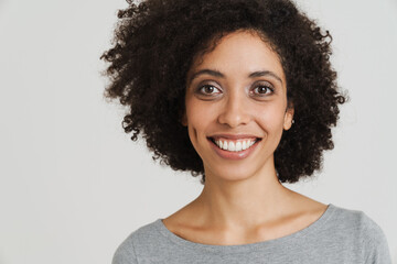 Young black woman with curly hair smiling and looking at camera