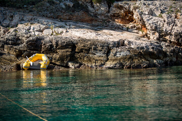 gelbes Gummiboot in der Sonne auf Felsen am Meer