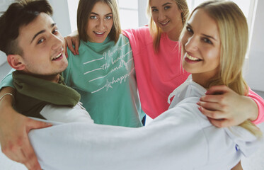 Happy smiling friends, group of young people standing and embracing together