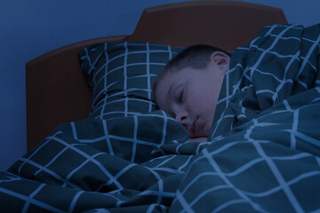 the boy sleeps in bed. the face of a child sleeping at night