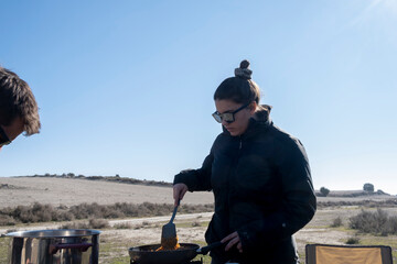 Mujer cocina en medio del campo