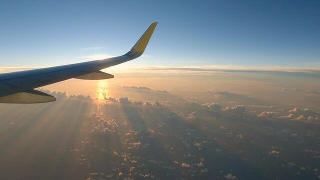 Airplane cloudy sunrise or sunset calm view right side of plane with sun slightly covered by wing