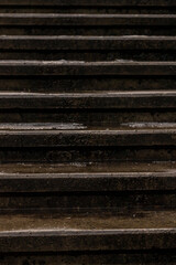 Vertical close-up photo of dark, wet, concrete set of steps at winter. Old weathered stone stairs texture for background. Pattern of vintage stairway. Urban lines in the city.  