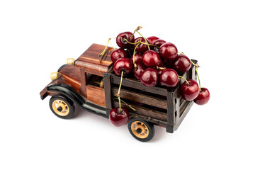 Ripe sweet cherries in a wooden toy truck on white background.