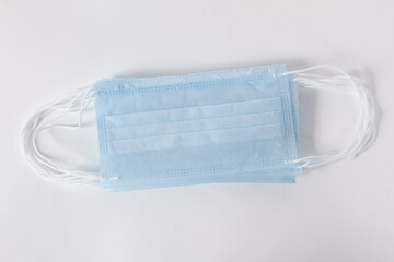Blue disposable surgical face mask top view. Protective mask with ear straps against coronavirus and bacteria isolated on white background. Healthcare medical hygiene concept
