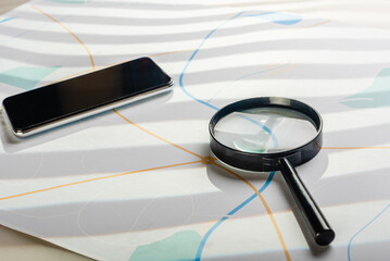 Modern smartphone with spying app and magnifying class against city map