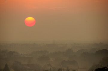 Zachód słońca nad spowitym w smogu miastem.