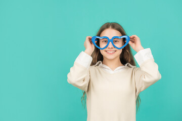 cheerful kid in party glasses on blue background with copy space, childhood