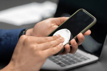 Hand of man with sanitizer for cleaning gadgets while pandemic