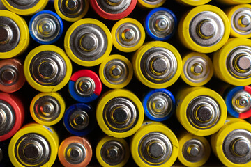 Background of colorful batteries. Close up top view on rows of selection of batteries. Many alcaline batteries. Macro.