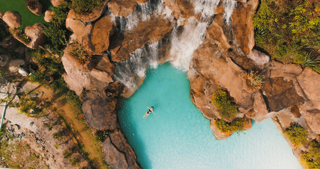 Girl swimming in beautiful crystal clear waterfall
