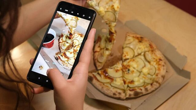 woman hand with smartphone photographing pizza at restaurant or cafe. Vegetarian pizza, vegetarian food, woman shoot vegetarian pizza