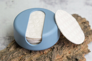 Reusable Cotton Rounds makeup remover in a container made from recycled ocean plastic on tree bark. Zero waste pads for to reduce environmental pollution.