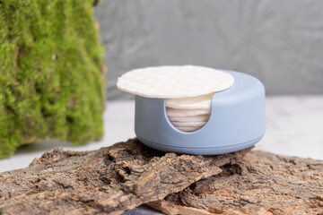 Reusable Cotton Rounds makeup remover in a container made from recycled ocean plastic on tree bark. Zero waste pads for to reduce environmental pollution.