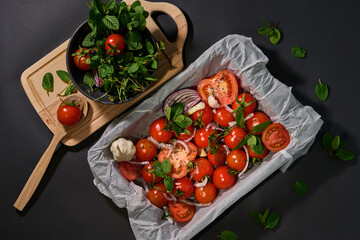 Ingredients for tomato soup. Tomatoes, onions, greens on a black background. Cook. Recipe. View from above
