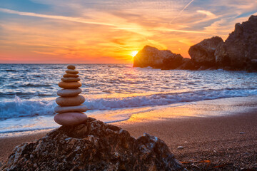 Concept of balance and harmony. Cairn stack of stones pebbles cairn on the beach coast of the sea in the nature on sunset. Meditative art of stone stacking