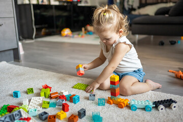 Caucasian child a little girl is playing in the constructor at home. Educational toys for children.