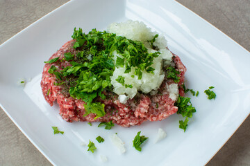 Meatball Preparation Ingredients in a bowl. ground beef, grated onion, parsley, black pepper, salt.