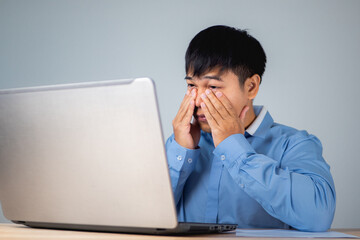 Business man pains his eyes when he looks at the laptop. He touches his eye by hands. Ophthalmology concept. This shot is medium close up portrait.