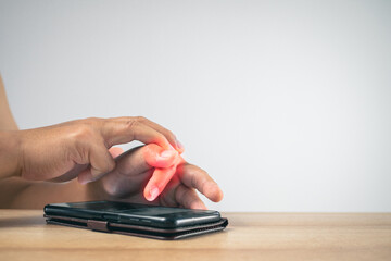 The man uses a mobile phone. Then his fingers pain. Office syndrome concept. Pain symptom area is...