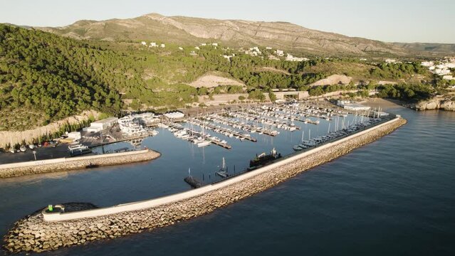Lateral drone flight view of a Small sports nautical club showing several mooring rows with dozens of docked recreational boats next to each other in Oropesa Del Mar, Spain