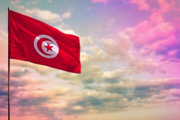 Fluttering Tunisia flag mockup with the space for your content on colorful cloudy sky background.
