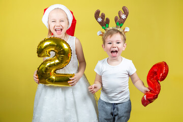 Adorable caucasian kids holding balloons with numbers and making funny faces