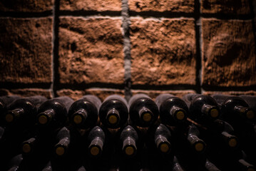 Old wine bottles in a old wine cellar stacked in rows. Dusty old green wine bottles whith corks. 