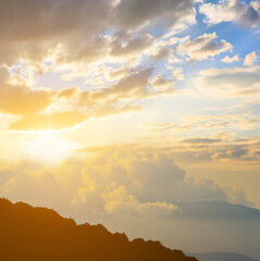 mount slope silhouette in dense clouds at the sunset, natural travel background