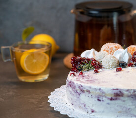 winter cake with berries and tangerines on a dark background, next  tea with lemon