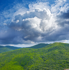 Obraz premium green mountain chain under dense cloudy sky