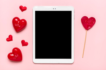 tablet for chooses gifts, makes purchase, two red hearts on pink table Top view Flat lay Holiday...