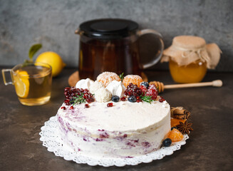winter cake with berries and tangerines on a dark background, next  tea with lemon