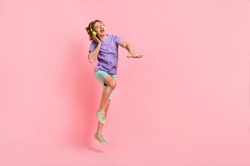 Full length body size view of attractive cheery crazy guy jumping listening hit dancing isolated over pink pastel color background