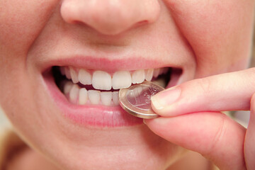 Zähne einer Frau beißen auf eine Euro-Münze