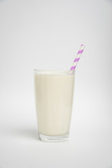 glass of milk with purple straw isolated on a white background