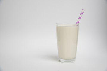 glass of milk with purple straw isolated on a white background