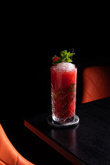 Strawberry mojito in dark moody bar garnished with mint