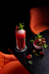 Strawberry mojito in dark moody bar garnished with mint
