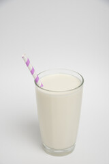 Milk glass with colored straw close-up on a white background