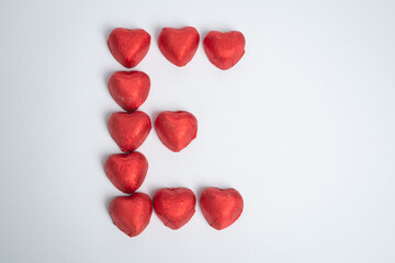 Chocolate red heart sweets in the form of the letter E for Valentine's Day on a white background