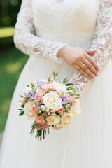 Beautiful wedding colorful bouquet in the hands of the bride. Wedding ring on the finger